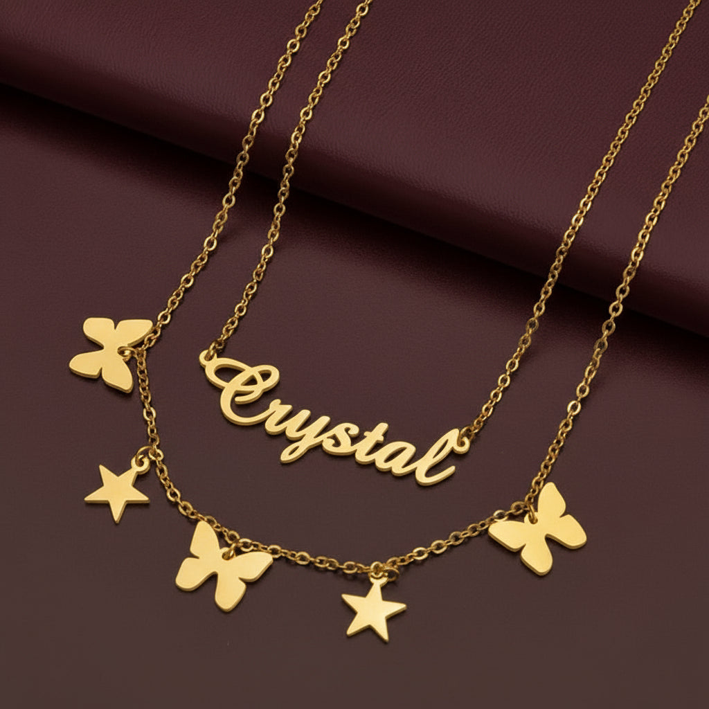 Gold necklace with 'Crystal' pendant and butterfly, star charms on a black background.
